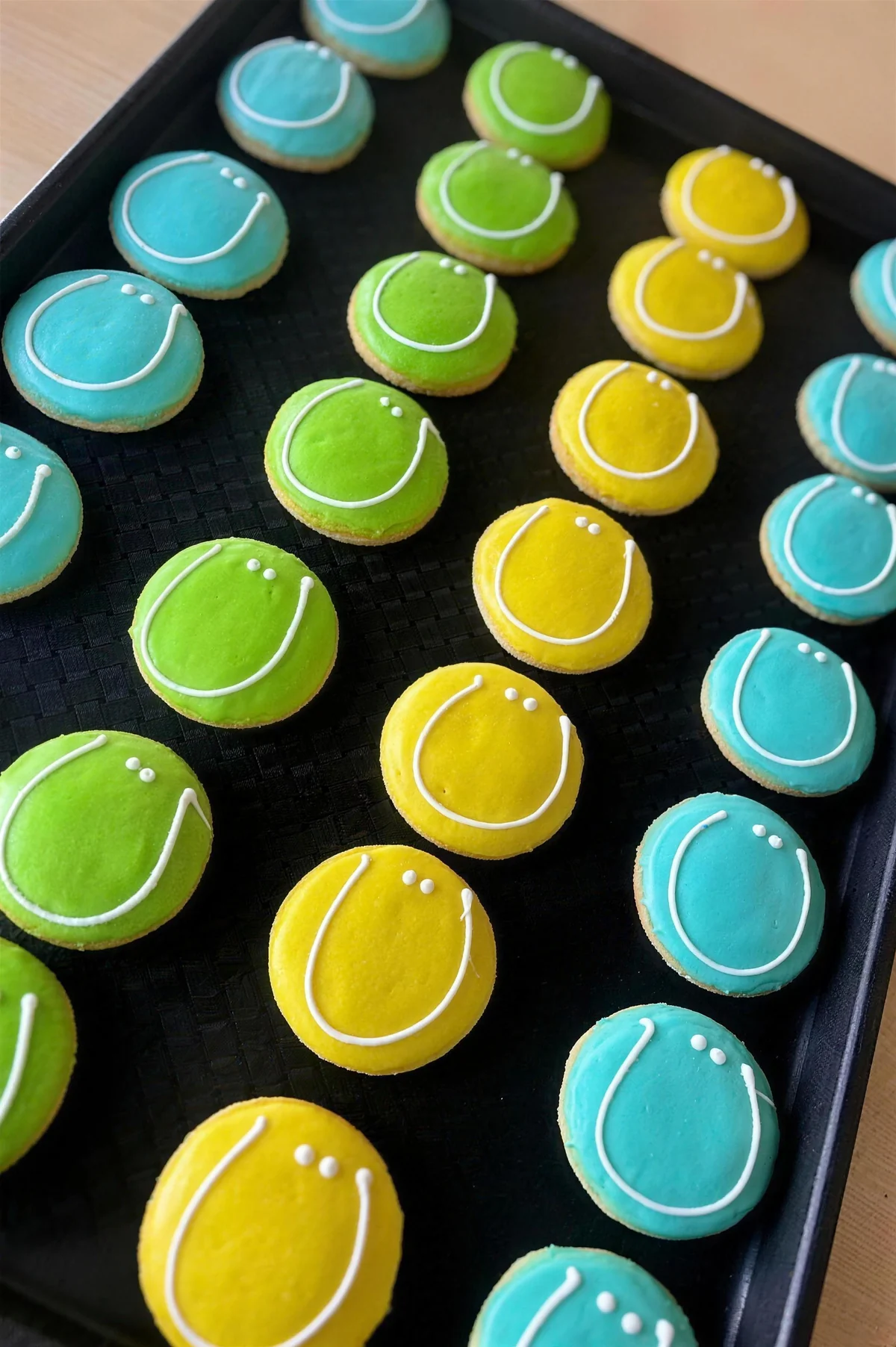 Blue, green and yellow iced smiley face sugar cookies on a tray
