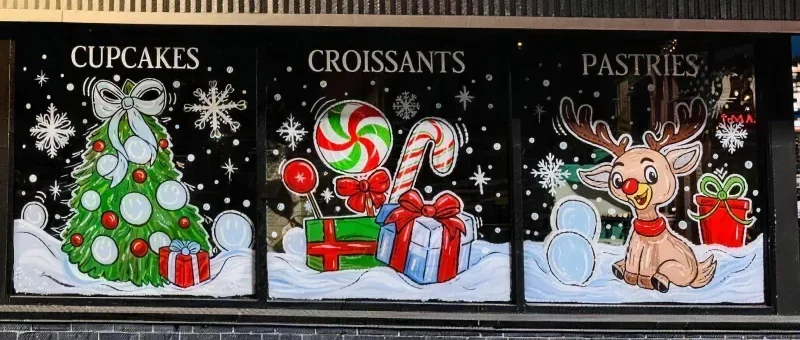 Hand painted Christmas windows on Julie's storefront: a tree, candy canes and a reindeer