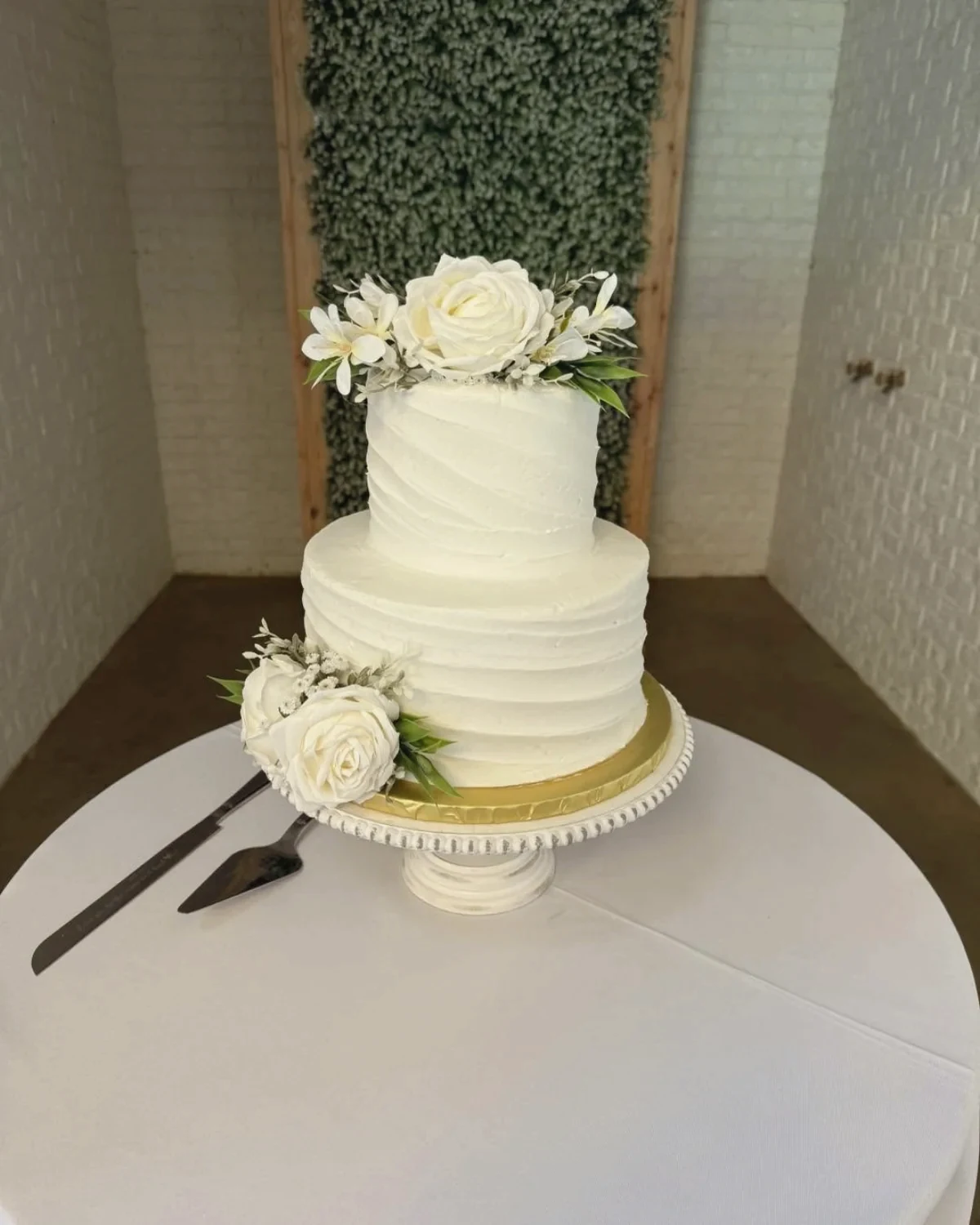 A textured two-tier cake with a white rose and gold stand