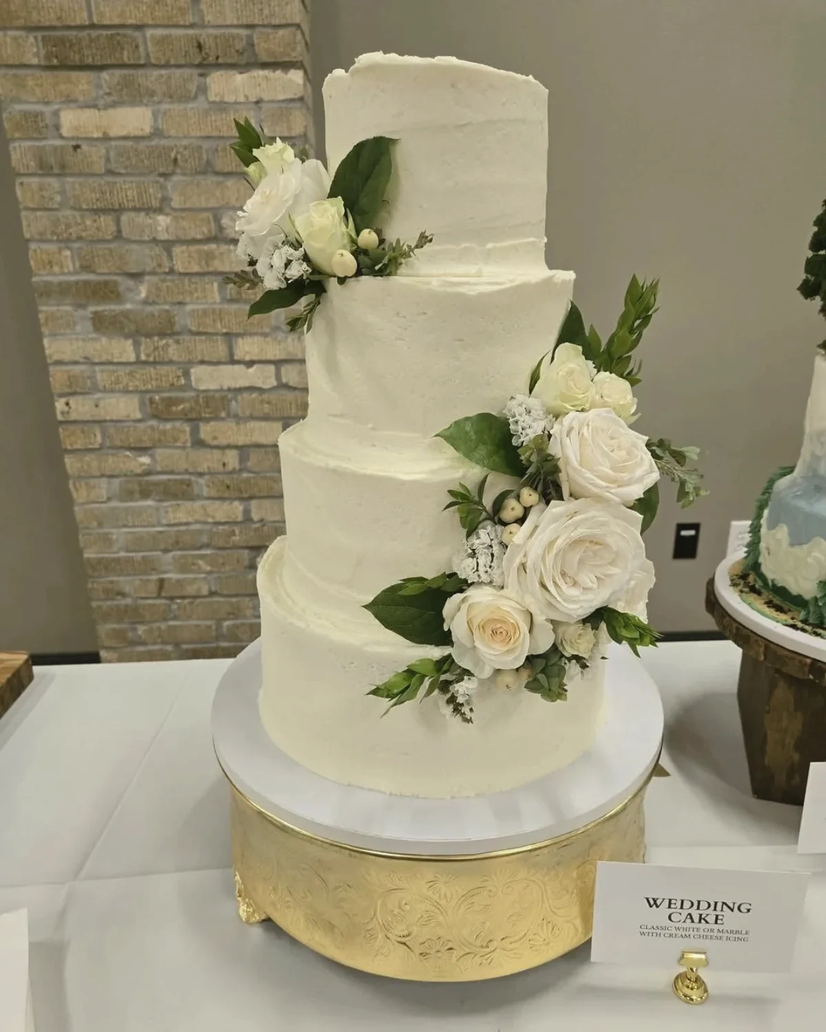 A tall textured cake with white roses and greenery