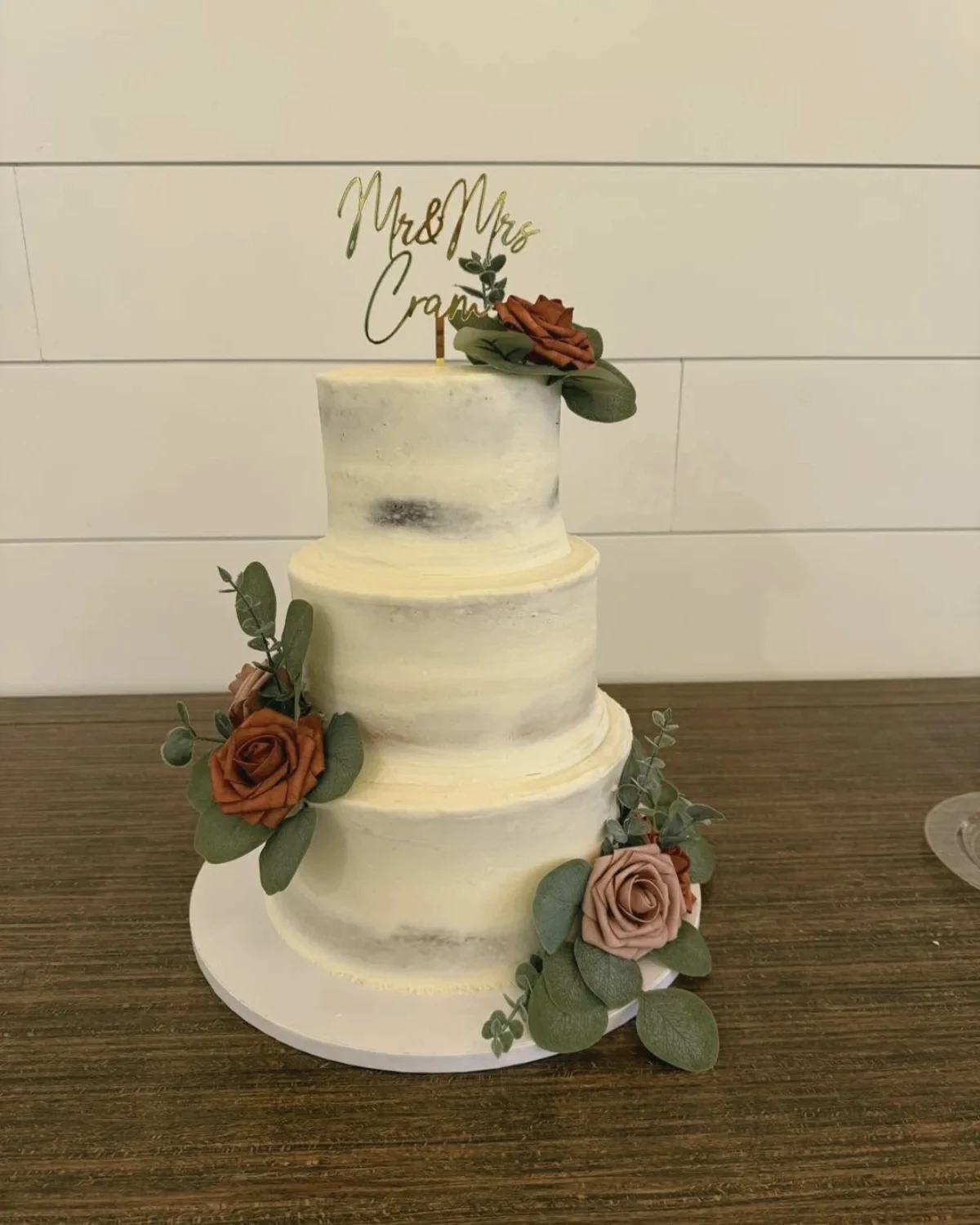 A semi-naked cake with rust and green flowers